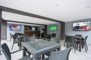 伊巴丹DE MANCHY HOTELS & SUITES的配有桌椅和电视的餐厅