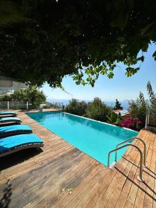 a swimming pool with lounge chairs on a wooden deck at Faralya Villa in Fethiye