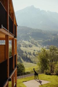 a giraffe walking on a sidewalk next to a building at Hotel Lech Da Sompunt in Badia