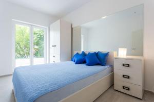 a bedroom with a bed with blue pillows and a window at Villa AMICA in Zaton