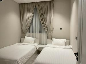 - 2 lits dans une chambre avec fenêtre dans l'établissement شقه فندقيه عالم الخيال خاصه ر, à Riyad