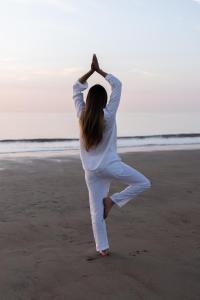 Eine Frau macht Yoga am Strand. in der Unterkunft Noordzee, Hotel & Spa in Cadzand-Bad