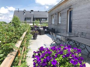 eine Terrasse mit lila Blumen, einem Tisch und Stühlen in der Unterkunft Die zwei Löwen Ferienwohnungen in Winterberg