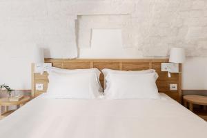 a bedroom with a white bed with white pillows at Masseria Auraterrae in Polignano a Mare