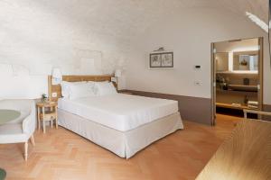 a bedroom with a large white bed and a chair at Masseria Auraterrae in Polignano a Mare