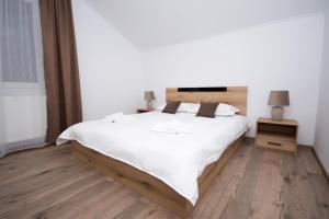 a bedroom with a large white bed and wooden floors at Casa Calina in Călimăneşti