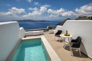 een patio met een zwembad en een tafel en stoelen bij Aura Suites in Firostefani
