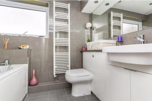 a bathroom with a toilet and a sink and a tub at Spacious 5 Bedroom 11 Guest Family House in Horsham in Roffey