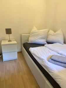 un letto con lenzuola bianche e un comodino con lampada di Wohnung in Landshuter Altstadt a Landshut