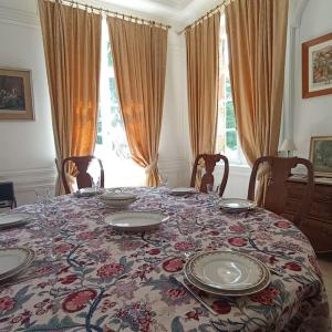 a table with plates on it with a floral table cloth at Château de Heuqueville in Heuqueville