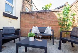 a patio with two chairs and two tables with wine glasses at Air Host and Stay - Dacy House, sleeps 7, free parking minutes from city centre in Liverpool