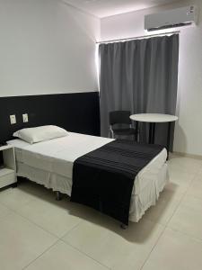 a bedroom with a bed and a table and a window at Hotel São Vicente in Araguaína