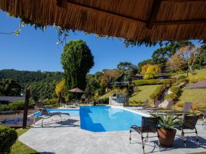 una piscina en un complejo con sillas y árboles en Pousada Varanda das Colinas, en Monte Verde