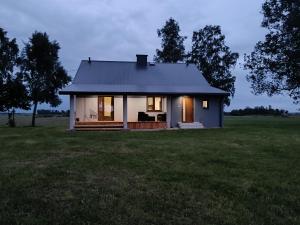a small white house in a grassy field at Siedlisko u Agi nad Biebrzą in Grabowo +4 photos