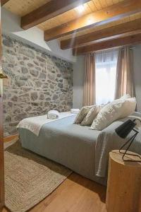1 dormitorio con 1 cama con pared de piedra en Casa Cubero - tucasaenlospirineos en Sallent de Gállego