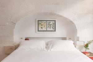 a white bedroom with a white bed with an archway at Masseria Auraterrae in Polignano a Mare
