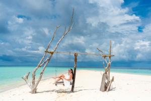 Una donna seduta su un'altalena sulla spiaggia di Turtle Maldives - Your Gateway to the Beach & Marine Adventures Await! a Omadhoo