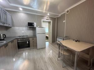 a kitchen with a table and a white refrigerator at Первая береговая линия, набережка in Aktau +12 photos