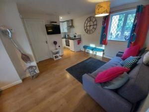 a living room with a blue couch and red pillows at Eastfield cottages in Devizes