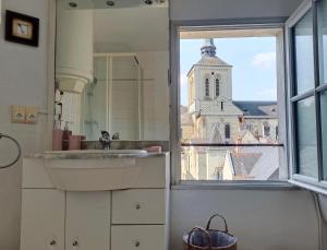 a bathroom with a sink and a window with a church at T2 vue sur Loire local vélo in Saumur +9 photos