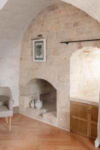 a stone fireplace in a living room with a chair at Masseria Auraterrae in Polignano a Mare