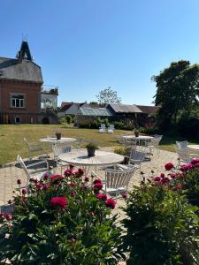 un patio con mesas, sillas y flores en Aggershøj pensionat, en Marstal