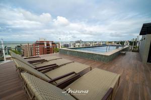 un balcón con sillas y una piscina en un edificio en Lindo apartamento de 2 quartos no Cayenne, en João Pessoa