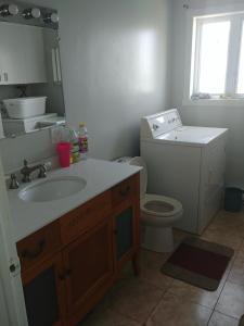 a bathroom with a sink and a toilet and a mirror at Les Logements Larocque in Shippagan