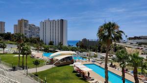 vista su un resort con piscina e palme di SUNSET WAVES relax apartment a Benidorm