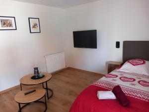 ein Schlafzimmer mit einem Bett und einem TV an der Wand in der Unterkunft Le Millésime de Sigo in Sigolsheim