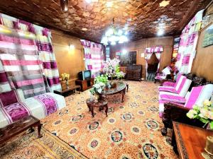 uma sala de estar com cadeiras cor-de-rosa e uma mesa em Aziz Palace Group Of Houseboats em Srinagar