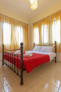 1 dormitorio con 1 cama con manta roja y ventanas en Valerios & Maria, en Gerani