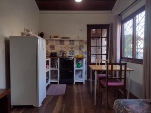 Una cocina con refrigerador y una mesa con sillas. en Casas Porto Belo, recanto em meio a natureza e próximo a praia, en Porto Belo 31 fotos más