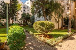 einen Gehweg mit Büschen und einem Baum in einem Park in der Unterkunft Appartement confortable residence koutoubia quartier nassim casablanca in Casablanca