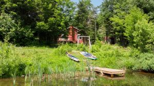 Saint-RaymondにあるLes Chalets Tourisma - Chalet dans les bois avec lac privé - Le Colibriの家の前の芝生に2隻の船が座っている