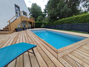 a swimming pool on a wooden deck with a blue table at Ty Breizh jet in Ergué-Gabéric