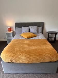 a bed with a yellow blanket and two pillows on it at Superb Lime Guest House in Shildon