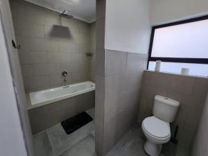 a bathroom with a toilet and a bath tub at East Park Inn in Polokwane