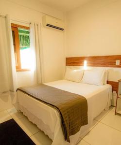 1 dormitorio con 1 cama blanca grande y ventana en Pousada Canto do Sol, en Barra Grande