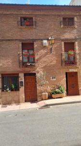 un bâtiment en briques avec des boîtes de fleurs sur les fenêtres et une rue dans l'établissement Apartamentos Jose Andres, à Viana