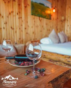 a wooden table with two wine glasses and a bed at Menzara Hotel & Restaurant in Sapanca