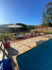a swimming pool with an umbrella and a table and chairs at CHÁCARA COM PISCINA CLIMATIZADA e JACUZZI in Socorro