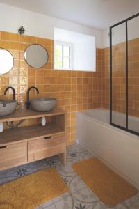 a bathroom with two sinks and a tub and a mirror at Escale de Gerbold in Gratot
