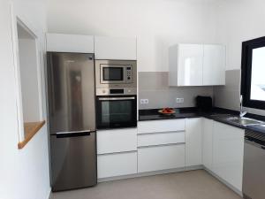 cocina con armarios blancos y nevera de acero inoxidable en Apartamentos Falcón en Tinajo