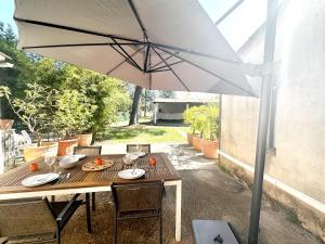 a wooden table with an umbrella on a patio at Magnifique Loft - Piscine - Tennis - Babyfoot in Nîmes