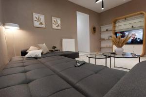 ein Wohnzimmer mit einem großen Sofa und einem TV in der Unterkunft Avli House in Iraklio