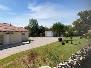 einen Hof mit einem Haus und einer Steinmauer in der Unterkunft Villa avec son spa privatif proche de Rocamadour in Gramat