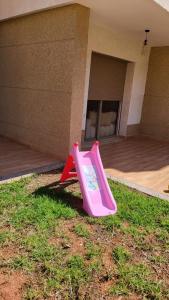 a pink slide in the grass in front of a building at Villa de luxe residence tamaris marina 6 piscines jardin parking in Saidia 