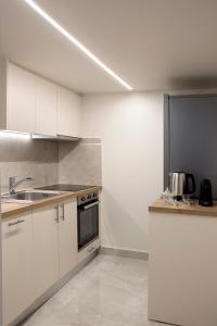una cocina con armarios blancos y fregadero en La Residence Athens, en Atenas