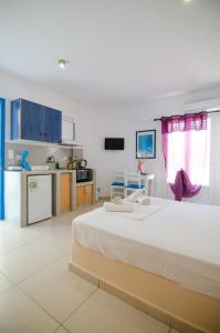 ein großes Schlafzimmer mit einem großen Bett und eine Küche in der Unterkunft Sunshine Studios in Mylopotas